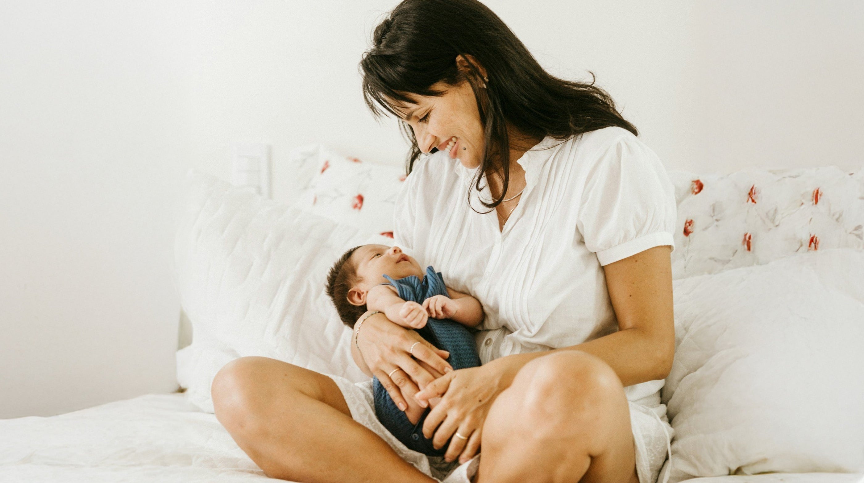 Breastfeeding Support: Mom on bed holding baby and smiling