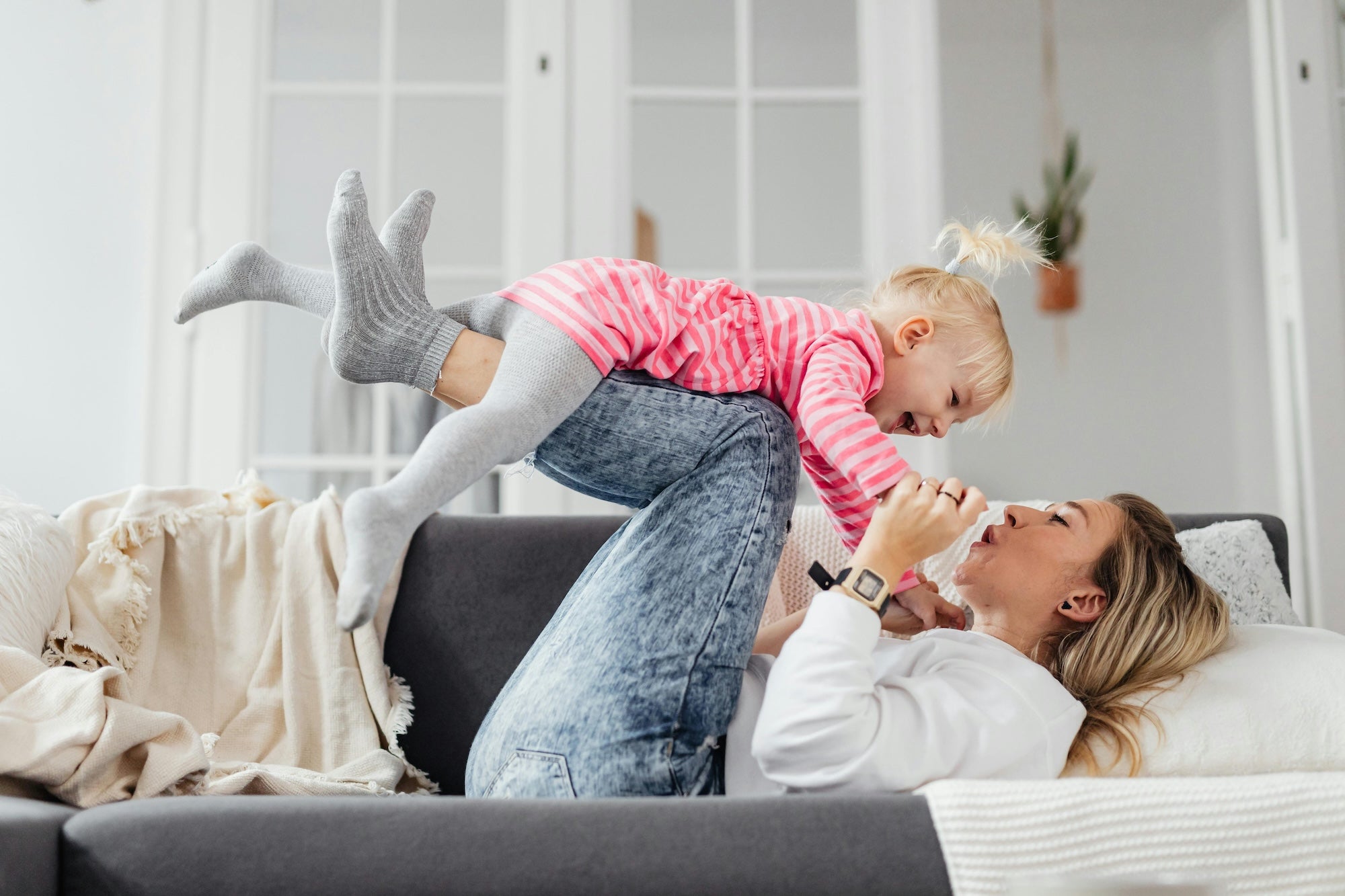 mom playig with toddler on couch