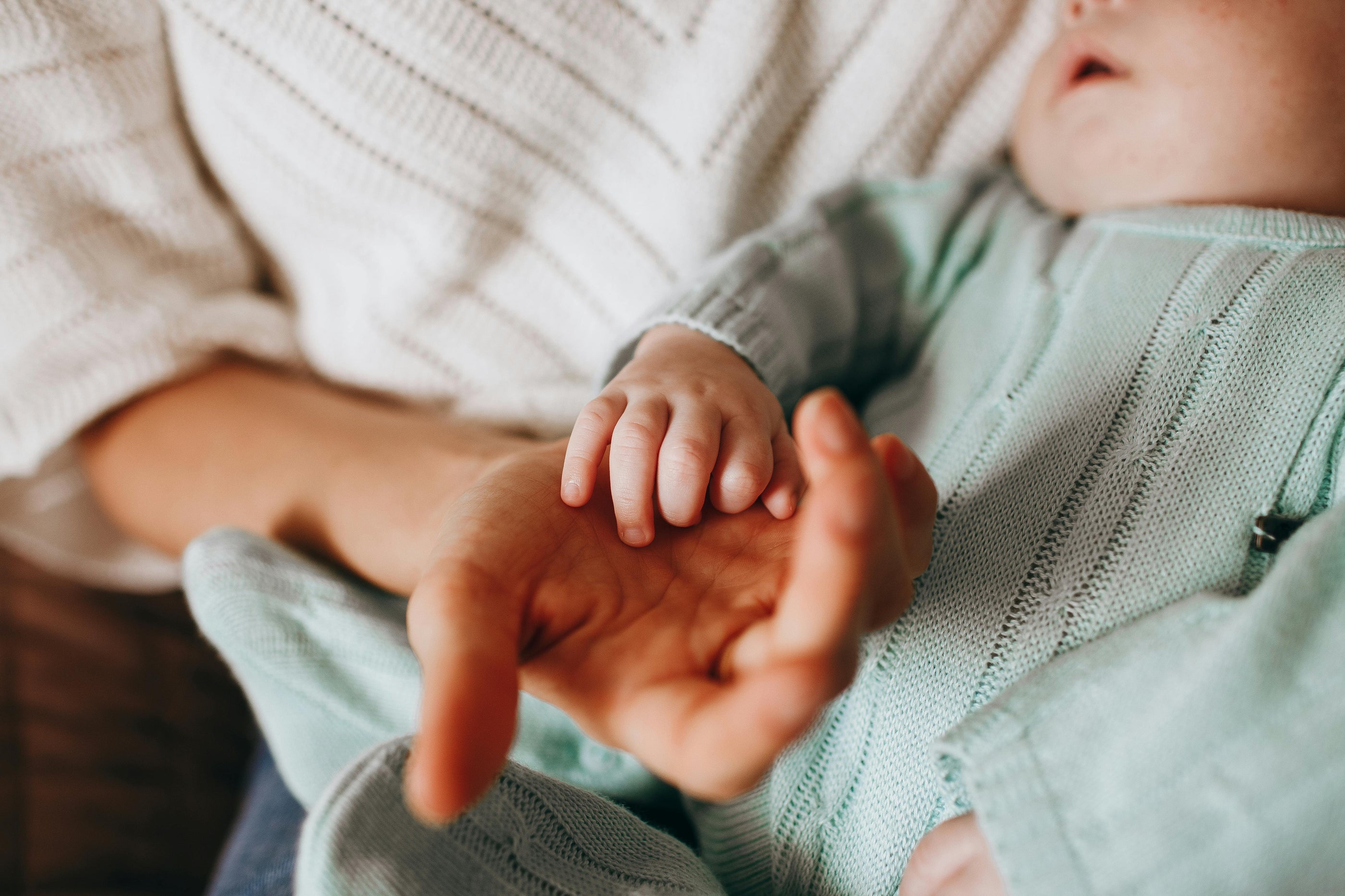 Sleeping baby holding moms hand