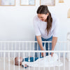 Smiling mother looking at her baby lying in a crib