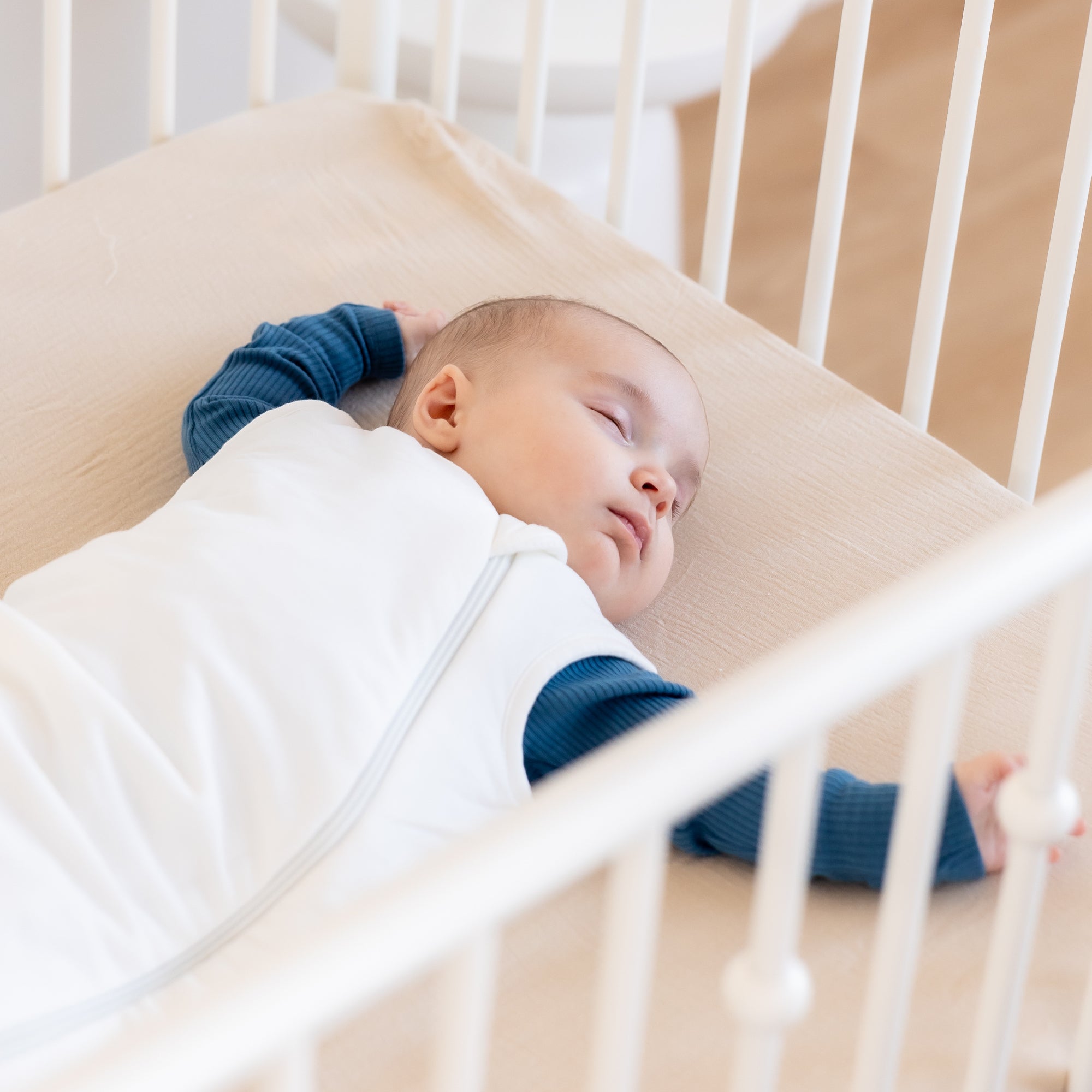 baby asleep in crib in sleep sack on back